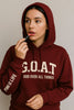 Person wearing a maroon hoodie with 'G.O.A.T. God Over All Things' text, applying lipstick.